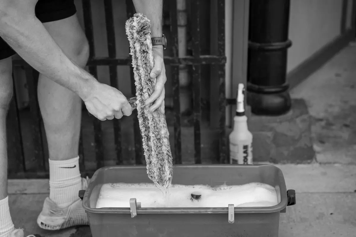 Rinsing a window washing sleeve in a bucket of solution